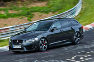 黑色Jaguar XF Sportbrake在綠草和護欄的賽道上奔馳。 — 美洲豹汽車 壁紙