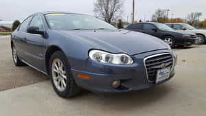 藍色 Chrysler 轎車停在戶外碎石停車場，有光禿的樹木和陰天。 — 克萊斯勒 壁紙