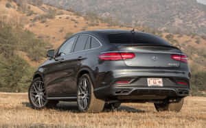 深灰色 Mercedes-AMG GLC 63 S Coupe 停在乾草地，背景有丘陵。 — Steam Deck OLED 壁紙