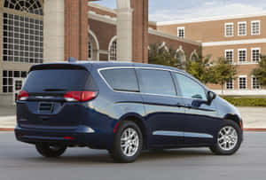 深藍色 Chrysler Pacifica 小型貨車停在磚砌建築外。 — Surface Pro 壁紙