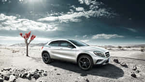 銀色SUV停泊在沙漠中，有紅葉樹和雲層天空 — Mercedes-Benz 壁紙