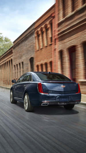日落時分，深藍色Cadillac CT6駛過紅磚建築。 — 凱迪拉克 壁紙