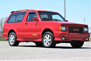 紅色GMC Typhoon SUV停泊在鋪砌的停車場，天空明亮 — 秋季 壁紙