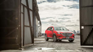 紅色Mazda CX-9 SUV停放在打開的工業車庫門之間，背景是城市天際線。 — 馬自達 壁紙