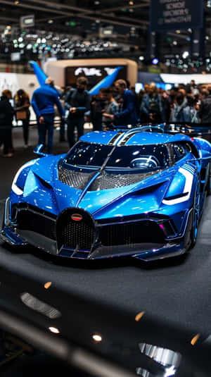 閃亮的藍色 Bugatti 超級跑車在車展上展出，周圍有人群。 — 布加迪 GIF 壁紙