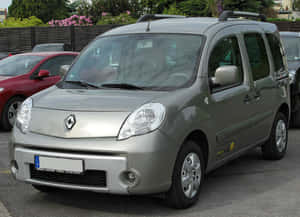 銀色雷諾Kangoo客貨車停在戶外停車場，靠近開花的灌木叢。 — 雷諾 壁紙