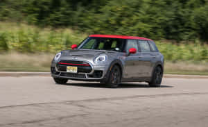 銀色MINI Cooper紅色車頂在道路上奔馳，背景綠色模糊。 — MacBook Pro 13 壁紙