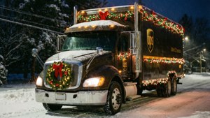 為聖誕節裝飾的UPS貨車在雪夜街道上行駛。