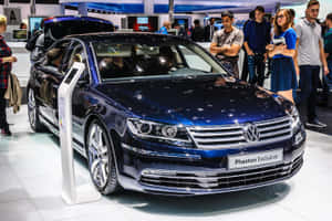 閃亮的藍色Volkswagen Phaeton Exclusive轎車在車展上展出，附近有與會者。 — Surface Pro 壁紙