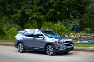 銀色GMC Terrain SUV停靠在河邊，背景有樹木。 — Surface Pro 壁紙