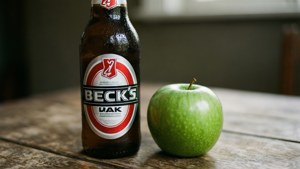 冰涼的Beck's啤酒旁邊放著一個青蘋果在木桌上。
