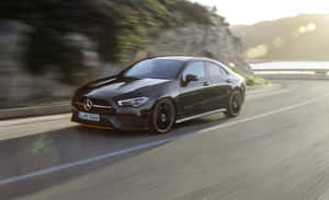 黑色Mercedes-AMG CLA 35 S E Performance在日落時分於海岸道路飛馳 — MacBook Air M1 壁紙
