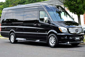 黑色 Mercedes-Benz Sprinter 廂型車停在靠近樹木和磚造建築的街道上。 — Mercedes-Benz 壁紙