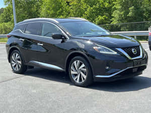 黑色日產Murano SUV停在陽光明媚的地方，後面有綠樹。 — 日產 壁紙