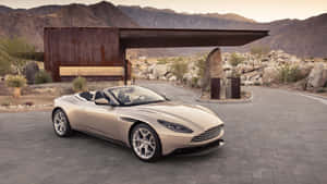 米色Aston Martin敞篷車停在現代沙漠莊園，後面有山脈。 — 奧斯頓馬丁 壁紙