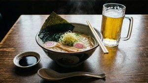 木桌上冒煙的拉麵碗與啤酒