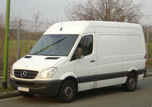 白色 Mercedes-Benz Sprinter 廂型車停放在街道上，靠近圍欄和光禿禿的樹木。 — Mercedes Benz C300 壁紙