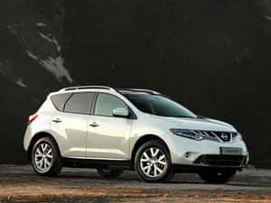 白色日產Murano SUV停泊在深色牆附近的礫石上。 — 日產 壁紙