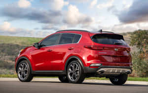 紅色Kia Sportage SUV停放在路邊，背景有丘陵和多雲的天空。 — Steam Deck 壁紙