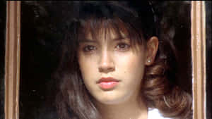 黑髮年輕女子透過木窗框觀看。 — 神力女超人1984 壁紙