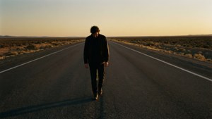 一個男人在日落時獨自走在沙漠公路上。