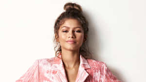 Zendaya 身穿粉紅色紋理西裝外套，頭髮盤成髮髻，背景是白色牆壁。 — 女演員 壁紙