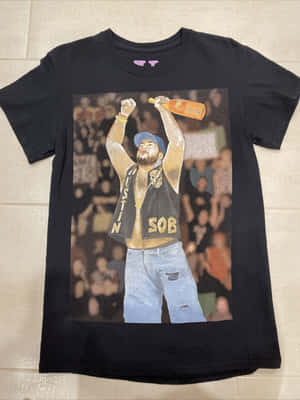 黑色T恤，圖案為男人在音樂會上舉瓶，瓷磚地板 — Vlone 壁紙