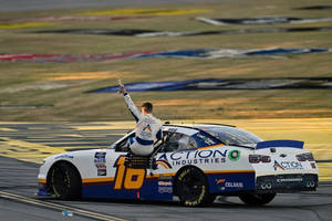 NASCAR車手在日落時分在賽車上舉起獎盃慶祝勝利。 — 跑車 壁紙