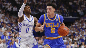 UCLA籃球運動員在擠滿觀眾的場館中運球越過肯塔基防守球員。 — 籃球 壁紙