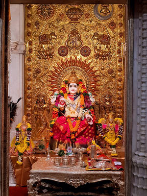 寺廟聖殿中飾有紅黃花朵的金色神像。 — Maa Durga 壁紙
