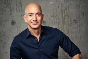 一位光頭男士身穿深藍色襯衫，在灰色混凝土牆前微笑。 — 亞馬遜 壁紙