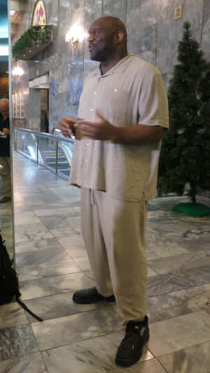 身穿米色休閒服的男士在大理石大廳聖誕樹附近做手勢。 — 運動 壁紙