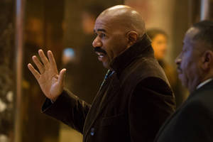 一位光頭留鬍鬚的男子在室內說話時做手勢。 — 桌面 壁紙