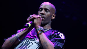 男歌手在紫色燈光下於舞台上表演，帶有紋身和珠寶。 — DMX 壁紙