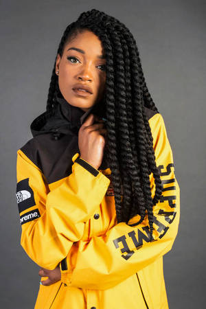 一位穿著黃色 Supreme x The North Face 外套的女士在攝影棚自信地擺姿勢。