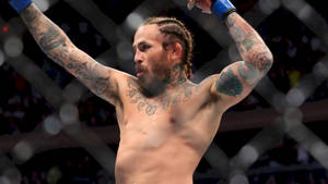 刺青MMA拳手在八角籠內高舉雙臂慶祝勝利。 — 運動 壁紙