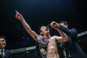 MMA拳手在八角籠中帶著冠軍腰帶和香檳噴霧慶祝勝利。 — 運動 壁紙