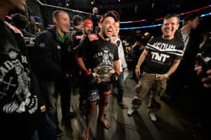 MMA拳手在八角籠中與冠軍腰帶和團隊慶祝勝利。 — 運動 壁紙