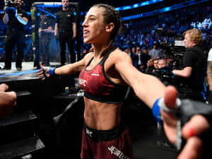 女MMA拳手在UFC八角籠中張開雙臂慶祝勝利。 — 高解析度 壁紙