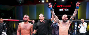 UFC拳手在八角籠中舉起拳頭慶祝勝利。 — 運動 壁紙