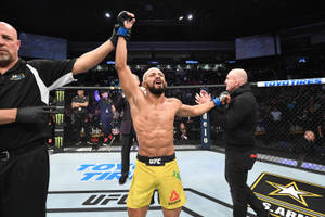 UFC拳手在八角籠中慶祝勝利，裁判舉起他的手臂。 — 終極格鬥冠軍賽 壁紙