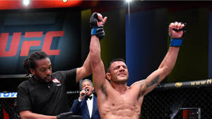 UFC拳手在八角籠中舉臂慶祝勝利。 — 勝利者 壁紙