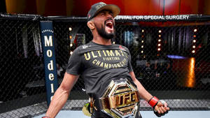 UFC拳手在八角籠內手持冠軍腰帶慶祝勝利。 — 運動 壁紙