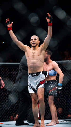 UFC拳手在八角籠內高舉雙臂慶祝勝利。 — 終極格鬥冠軍賽 壁紙