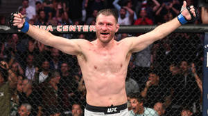 UFC拳手在八角籠內高舉雙臂慶祝勝利。 — 運動 壁紙