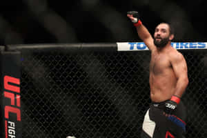 UFC拳手在八角籠內高舉拳頭慶祝勝利。 — 運動 壁紙