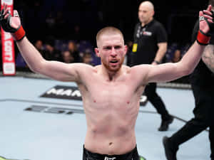 UFC拳手在八角籠內高舉雙臂慶祝勝利。 — 終極格鬥冠軍賽 壁紙