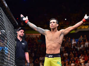 UFC拳手在八角籠內高舉雙臂慶祝勝利。 — 終極格鬥冠軍賽 壁紙