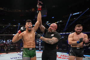 UFC拳手贏得比賽，裁判在八角籠內舉起他的手。 — 勝利 壁紙