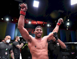 UFC拳手在八角籠內高舉雙臂慶祝勝利。 — 運動 壁紙